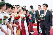 Der japanische Ministerpräsident Shinzo Abe geht am 06.06.2015 auf dem Flughafen München an einer Trachtengruppe vorbei.
