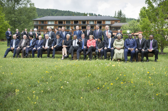 Die G7 sitzen zusammen mit den Outreach-Gästen zum Familienfoto auf einer Bank.