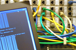 Ein Laptop steht vor Netzwerkkabeln in einem Serverschrank